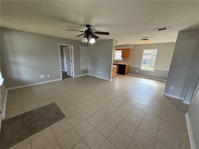 unfurnished living room featuring visible vents, baseboards, ceiling fan, and light tile patterned flooring