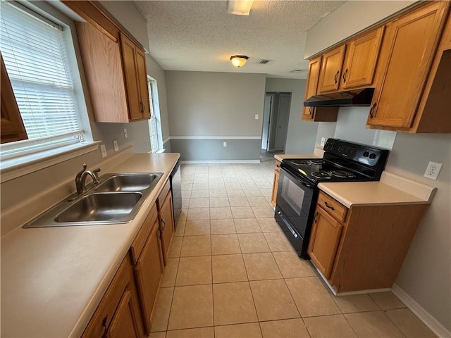 kitchen with black electric range oven, under cabinet range hood, a sink, a textured ceiling, and brown cabinetry