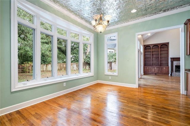 interior space featuring a fireplace, wood-type flooring, a wealth of natural light, and a notable chandelier