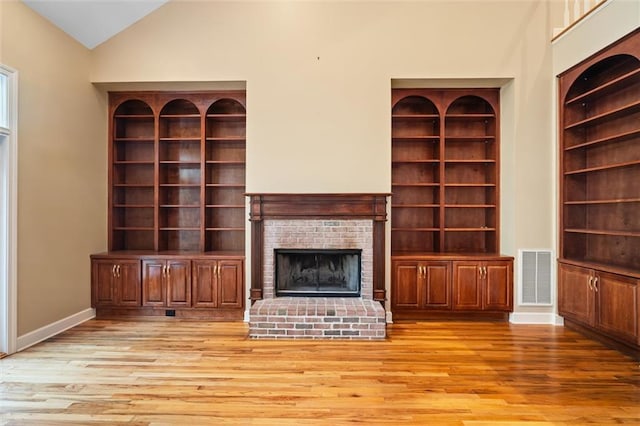 unfurnished living room with a fireplace, light hardwood / wood-style floors, and high vaulted ceiling