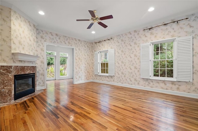 unfurnished living room with ceiling fan, a fireplace, wood-type flooring, and ornamental molding