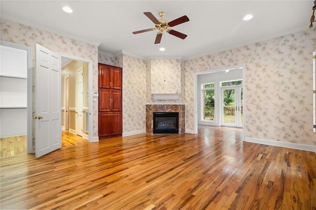 unfurnished living room featuring a fireplace, light hardwood / wood-style floors, ceiling fan, and crown molding