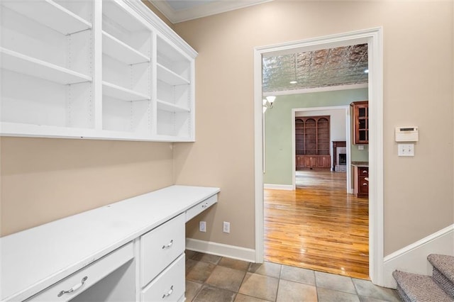 interior space featuring wood-type flooring, built in desk, and ornamental molding