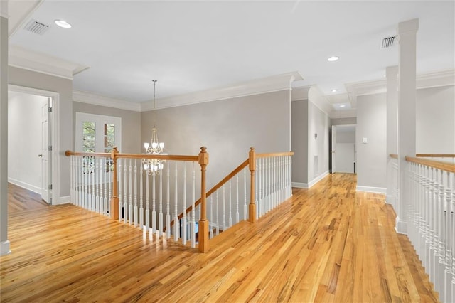 hallway featuring a notable chandelier, crown molding, and light hardwood / wood-style flooring