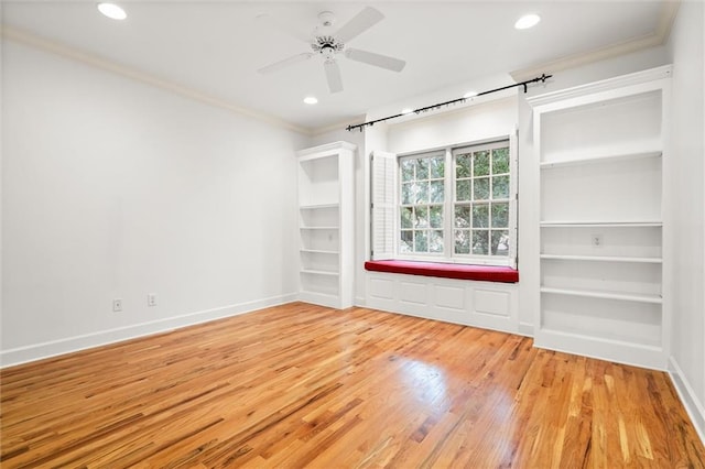 unfurnished room with built in shelves, light hardwood / wood-style flooring, ceiling fan, and ornamental molding