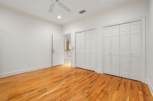 unfurnished bedroom featuring ceiling fan, two closets, ornamental molding, and light hardwood / wood-style flooring