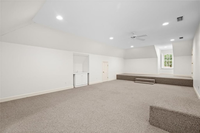 carpeted spare room with ceiling fan and vaulted ceiling