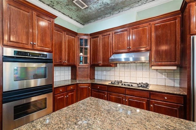 kitchen with appliances with stainless steel finishes, tasteful backsplash, light stone counters, and crown molding