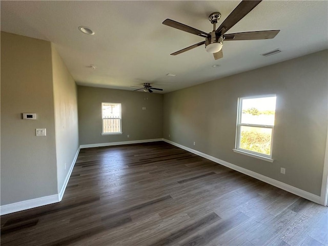 unfurnished room with baseboards, visible vents, ceiling fan, and dark wood-type flooring
