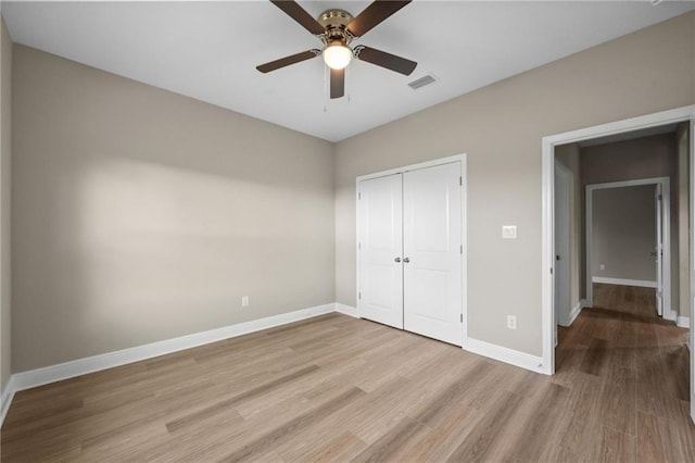 unfurnished bedroom with a closet, visible vents, baseboards, wood finished floors, and a ceiling fan