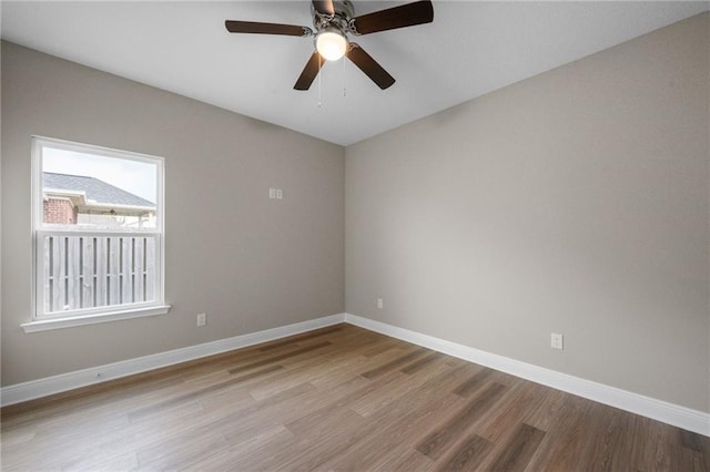 empty room with a ceiling fan, baseboards, and wood finished floors
