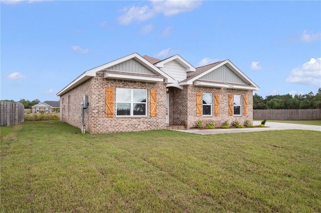 view of front facade with brick siding, a front yard, and fence