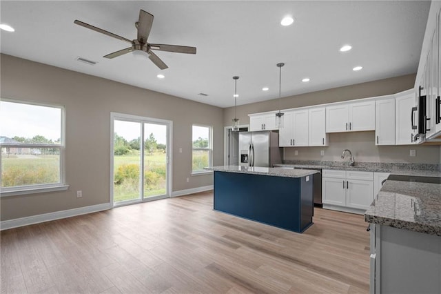 kitchen with light wood-style flooring, visible vents, stainless steel fridge, a ceiling fan, and a center island
