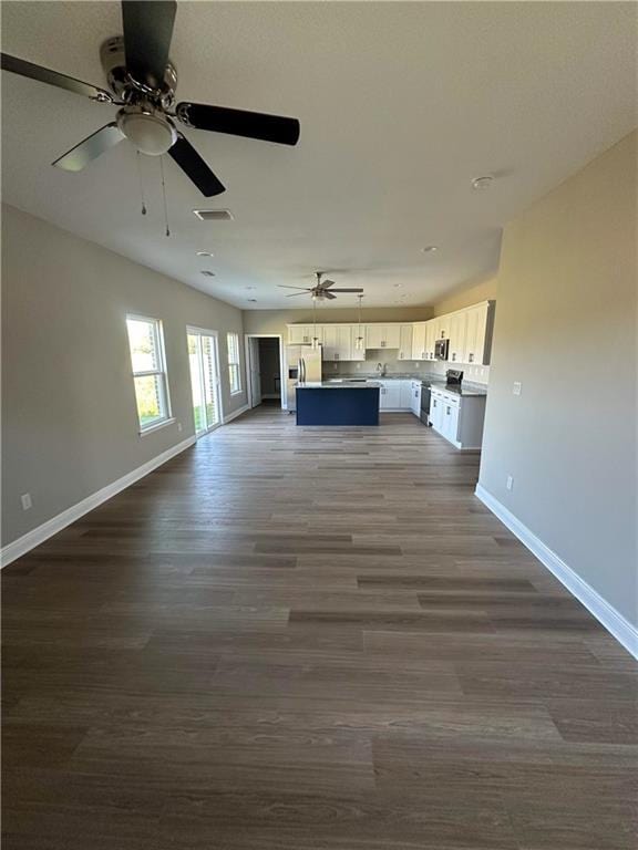 unfurnished living room with dark wood finished floors, baseboards, ceiling fan, and visible vents