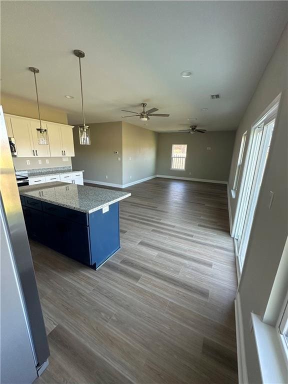 kitchen with baseboards, white cabinetry, visible vents, and a center island