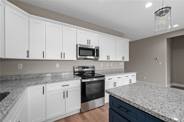 kitchen with white cabinetry, appliances with stainless steel finishes, hanging light fixtures, light wood-style floors, and blue cabinetry