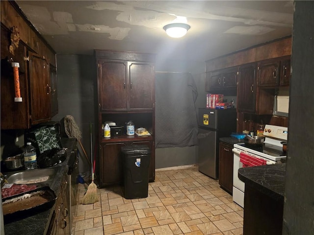 641 Baldwin Dr, Mobile, AL 36610 - kitchen with white electric stove, dark countertops, light stone finish flooring, freestanding refrigerator, and dark brown cabinets