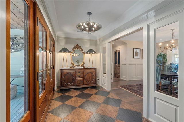 hallway featuring crown molding, an inviting chandelier, and dark hardwood / wood-style flooring