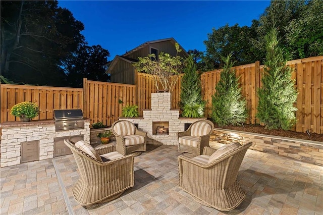 view of patio featuring area for grilling, grilling area, and an outdoor stone fireplace