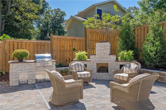 view of patio with area for grilling, an outdoor stone fireplace, and grilling area