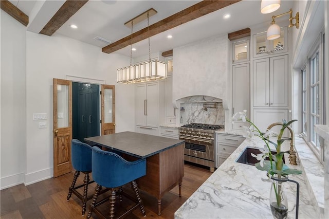 kitchen with beam ceiling, double oven range, plenty of natural light, and pendant lighting