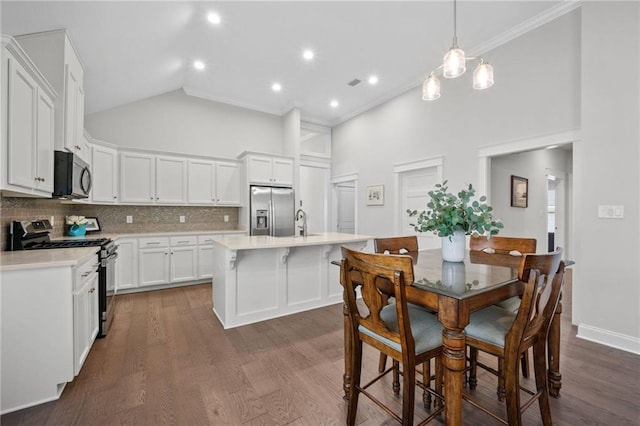 kitchen with decorative backsplash, high vaulted ceiling, stainless steel appliances, and light countertops