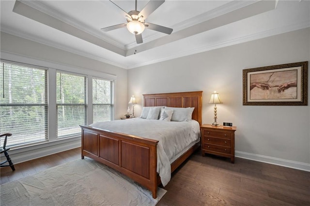 bedroom featuring baseboards, crown molding, a tray ceiling, and wood finished floors