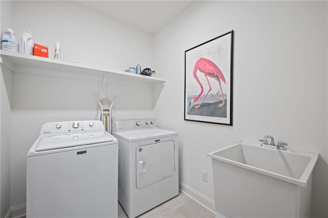 clothes washing area featuring laundry area, baseboards, a sink, and washing machine and clothes dryer