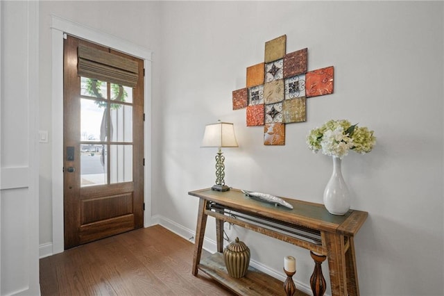 doorway with baseboards and wood finished floors