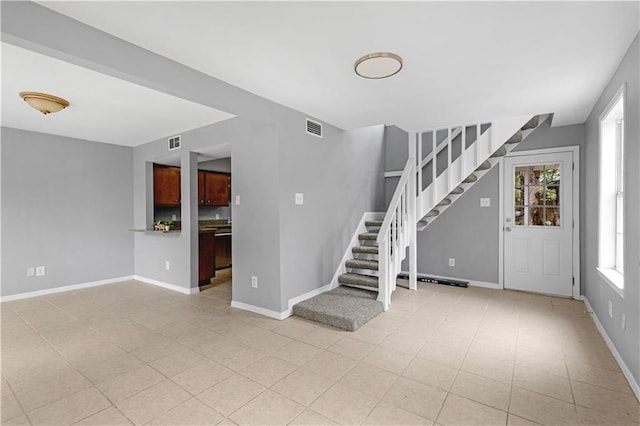 unfurnished living room with stairway, baseboards, light tile patterned floors, and visible vents