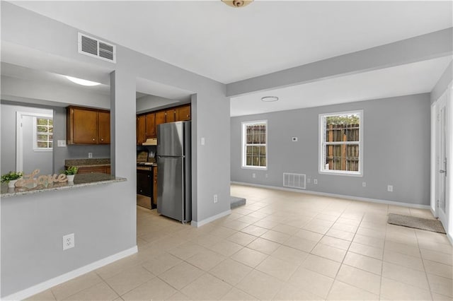 kitchen with appliances with stainless steel finishes, brown cabinetry, visible vents, and light tile patterned flooring