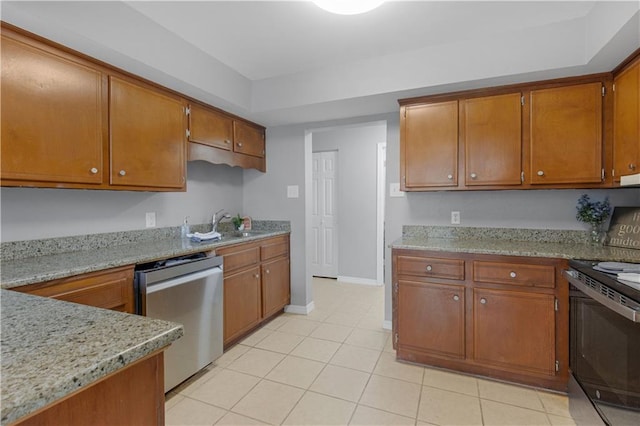 kitchen with stainless steel appliances, brown cabinets, a sink, and light stone countertops