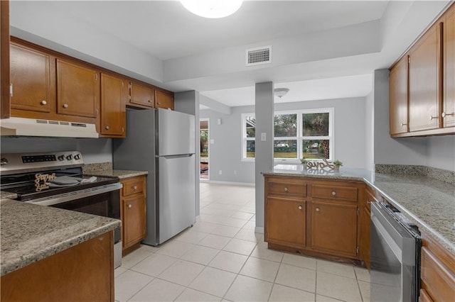 kitchen with under cabinet range hood, visible vents, stainless steel appliances, and brown cabinetry