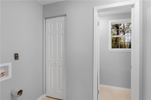 clothes washing area with hookup for a washing machine, hookup for an electric dryer, light tile patterned flooring, laundry area, and baseboards