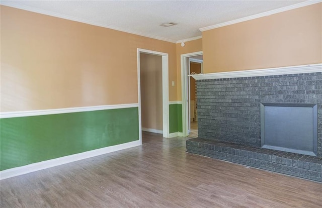 unfurnished living room with hardwood / wood-style flooring, crown molding, and a brick fireplace