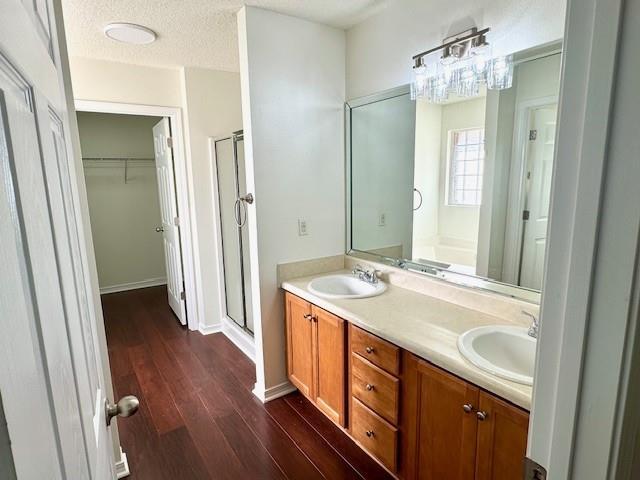 bathroom with vanity, hardwood / wood-style flooring, a shower with door, and a textured ceiling