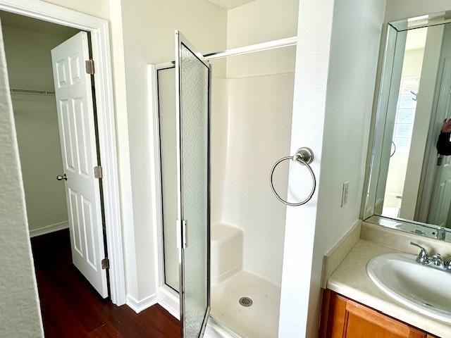 bathroom featuring walk in shower, vanity, and wood-type flooring