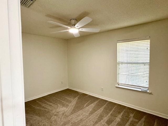 spare room with ceiling fan, dark carpet, and a textured ceiling