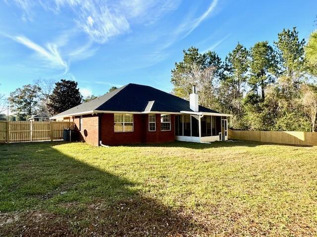 back of house featuring a sunroom and a lawn