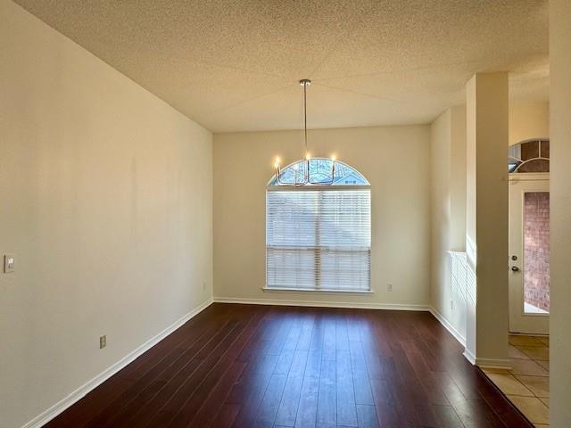 spare room featuring dark wood-type flooring and a textured ceiling