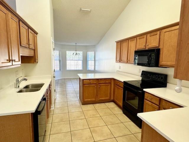 kitchen featuring light tile patterned flooring, sink, vaulted ceiling, kitchen peninsula, and black appliances