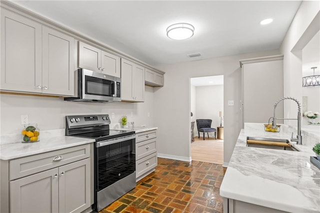 kitchen featuring gray cabinets, appliances with stainless steel finishes, sink, and light stone counters