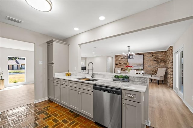 kitchen featuring sink, gray cabinetry, an inviting chandelier, dishwasher, and kitchen peninsula