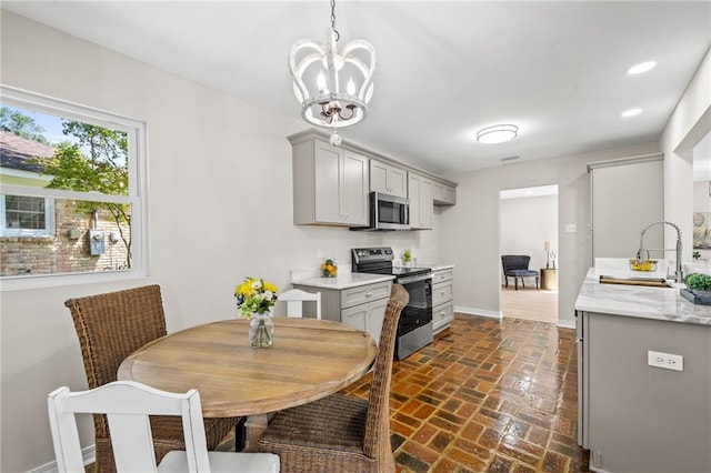 kitchen with gray cabinets, decorative light fixtures, sink, a notable chandelier, and stainless steel appliances