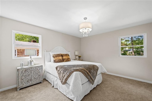 carpeted bedroom featuring multiple windows and an inviting chandelier