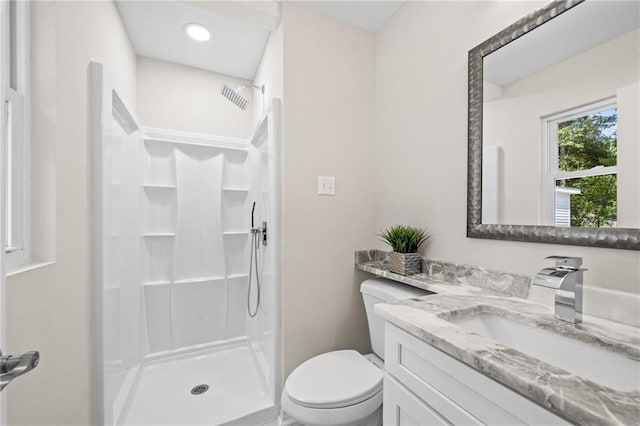 bathroom with walk in shower, vanity, and toilet