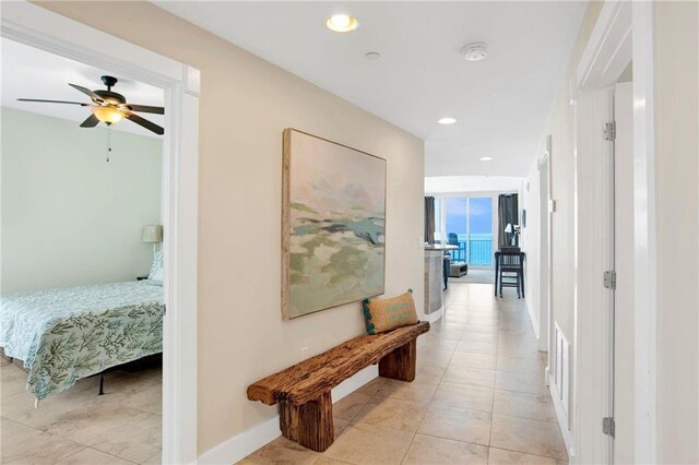hall with baseboards, light tile patterned floors, and recessed lighting