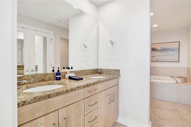 bathroom featuring double vanity, a bath, and recessed lighting