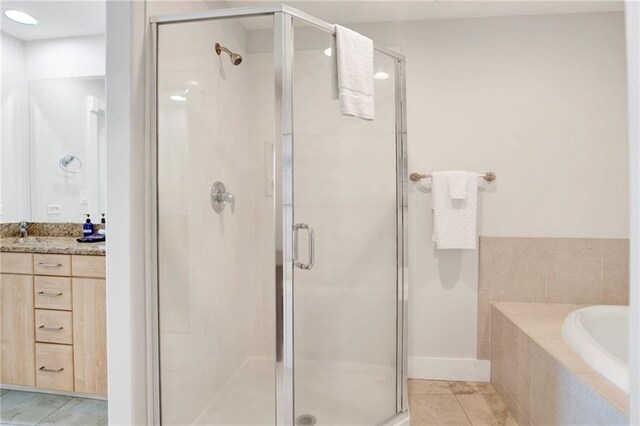 bathroom with a shower stall, tile patterned floors, vanity, and a bath
