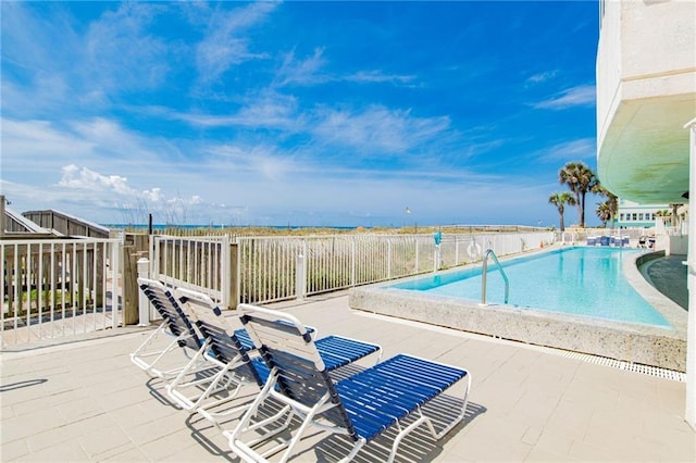 community pool with a patio area and fence